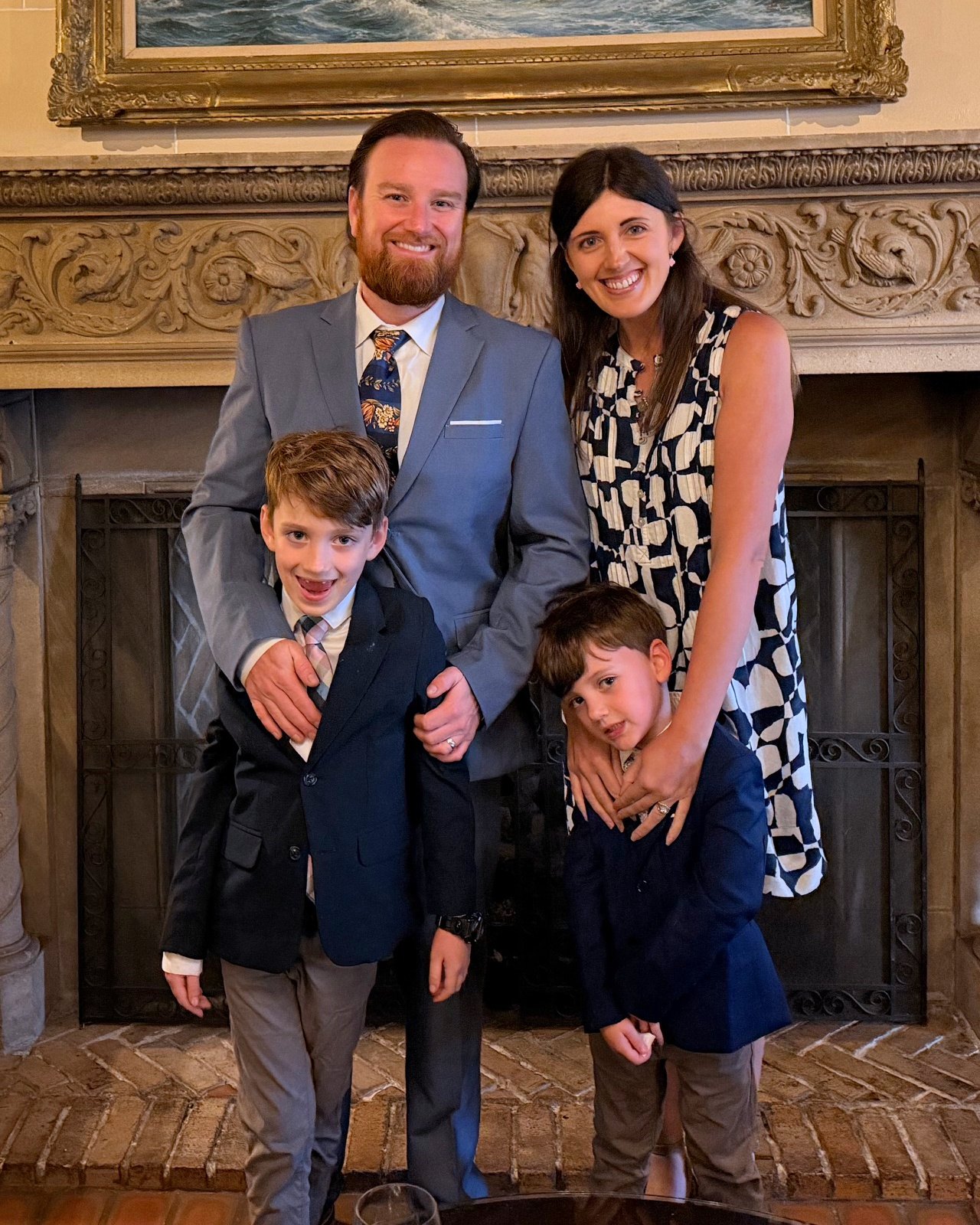 Andrew McCann with his family, standing together in front of a fireplace